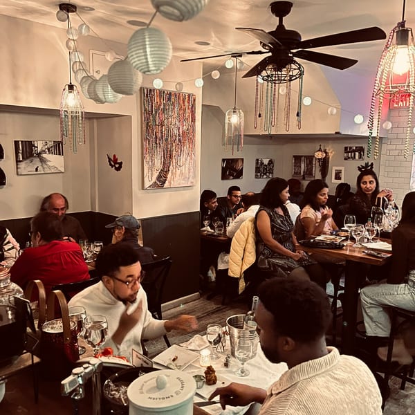 Diners enjoying a meal in a restaurant with festive Mardi Gras-themed decorations and warm lighting.