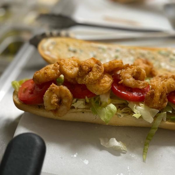 A Krewe of McGinley Square shrimp po'boy with fried shrimp, lettuce, and tomatoes on a baguette.